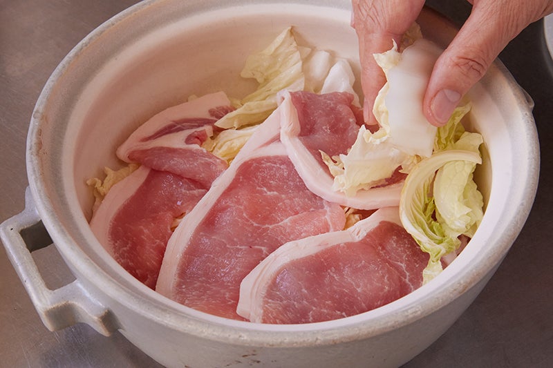 白菜、豚肉、塩を鍋中で重ねていく様子