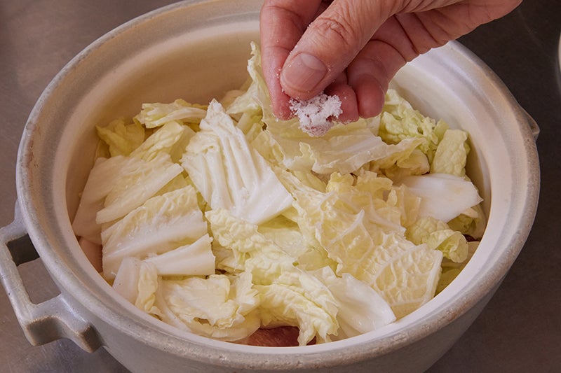 白菜、豚肉、塩を鍋中で重ねていく様子