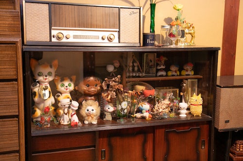 猫の置物や子供の人形など昭和の置物がおさめられている飾り棚