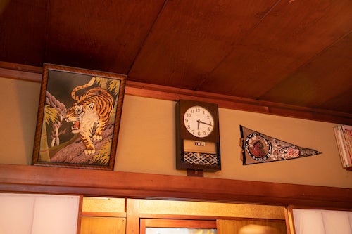 ペナントと虎の絵画、振り子時計がかけられた壁