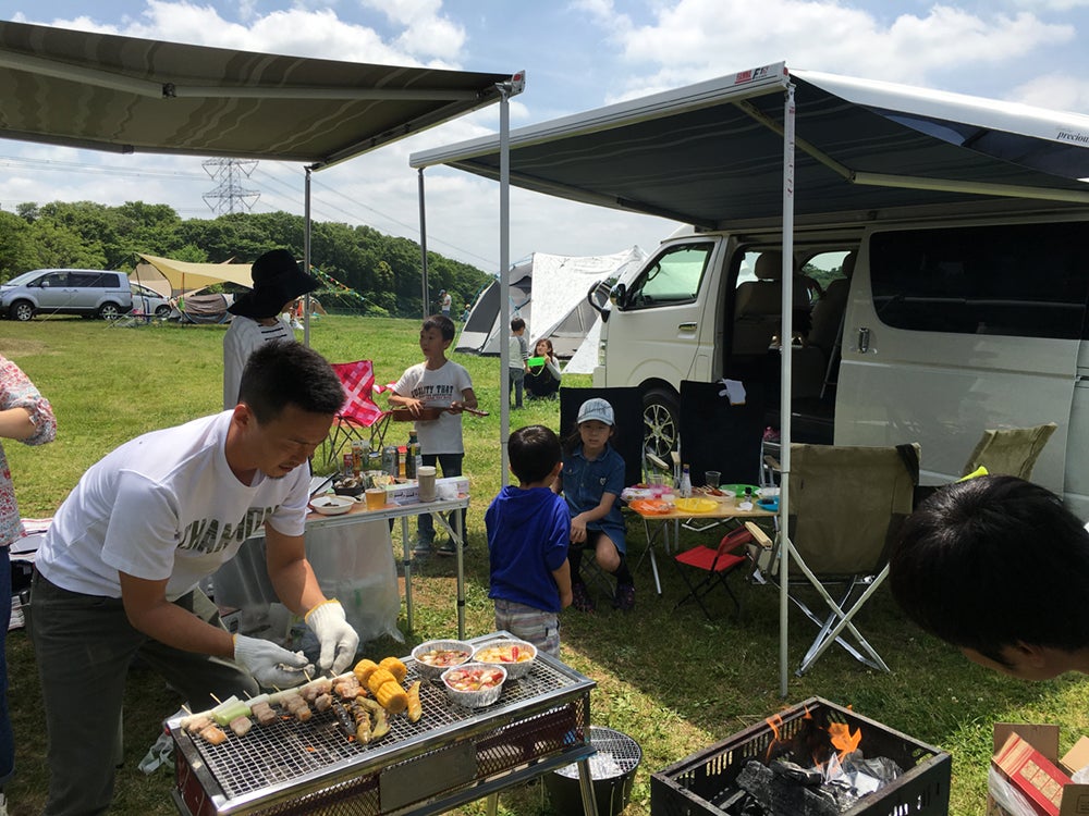 キャンピングカーでバーベキューをする人々