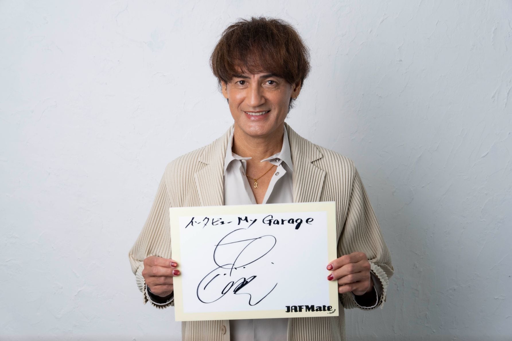 サインを持つ本並健治さん