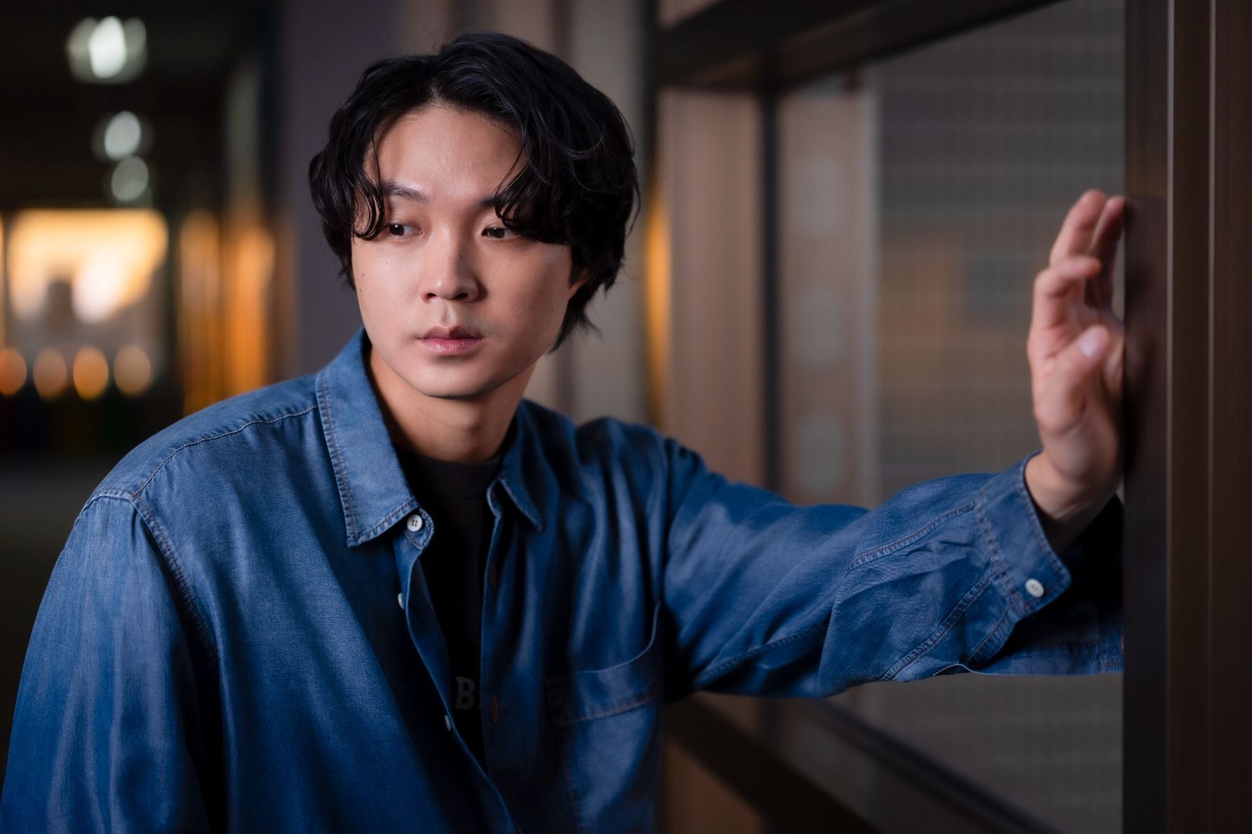 夕暮れ時の柔らかな光に包まれ、少しアンニュイな表情を見せる磯村勇斗氏のカット