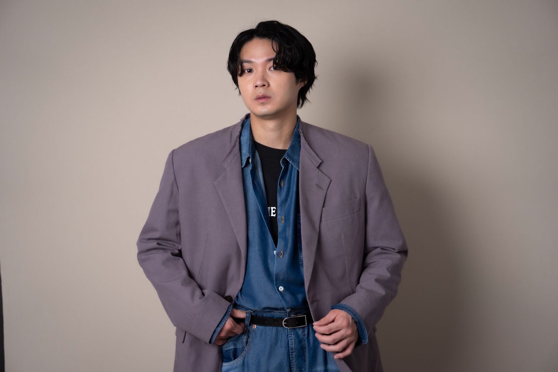 取材時のスタイリッシュな衣装を着こなし、カメラに向けてクールな視線を送る磯村勇斗の半身ショット