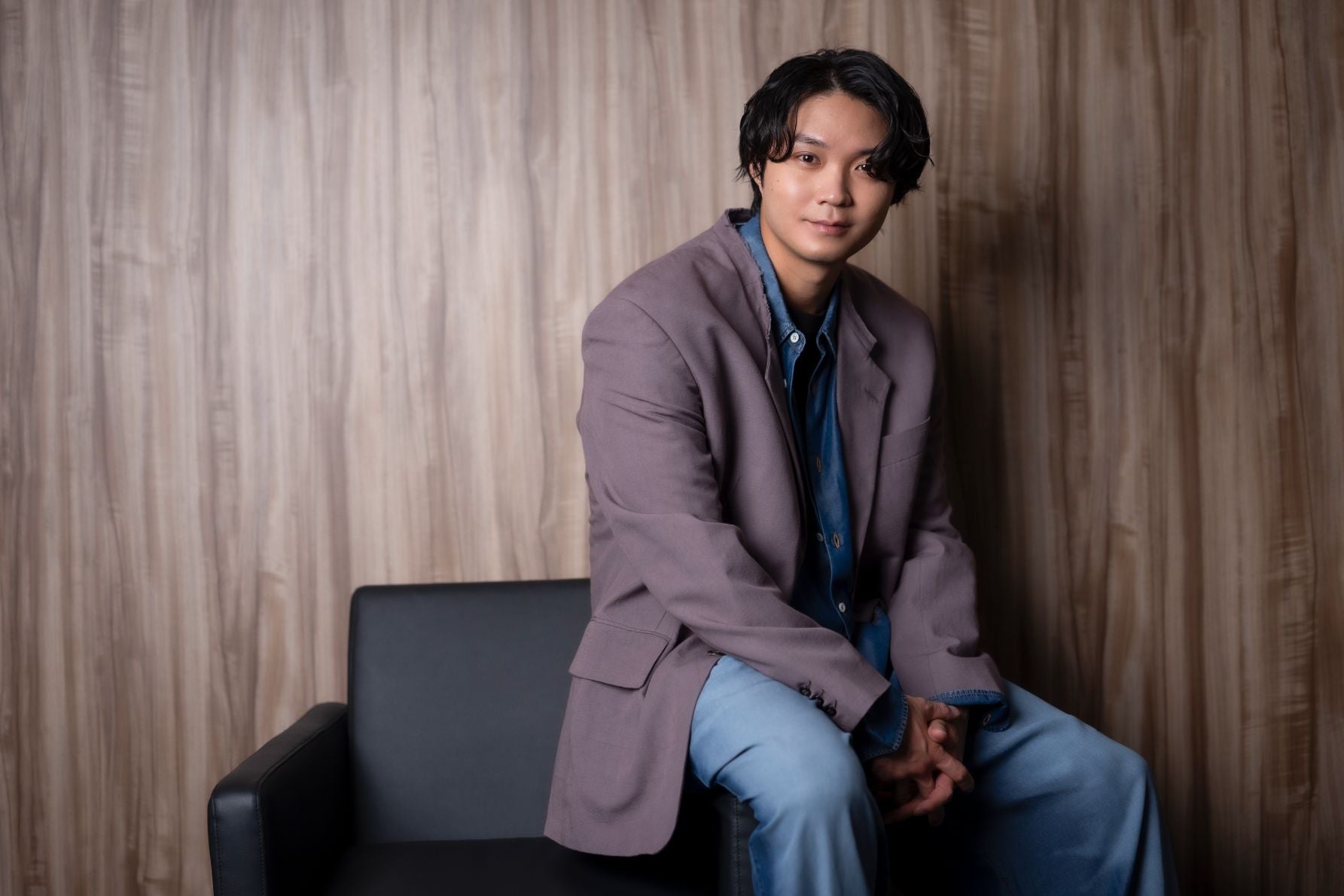 落ち着いた雰囲気のインタビュー場所で、リラックスして質問に応じる磯村勇斗の自然体なポートレート