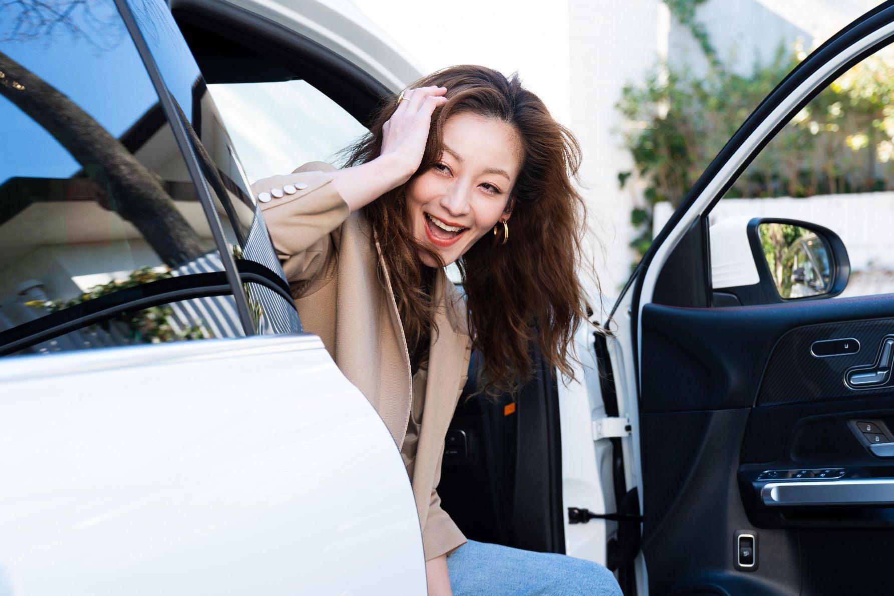 GLBの運転席に座り、窓から顔を出して楽しそうに笑う西山茉希さんのポートレート