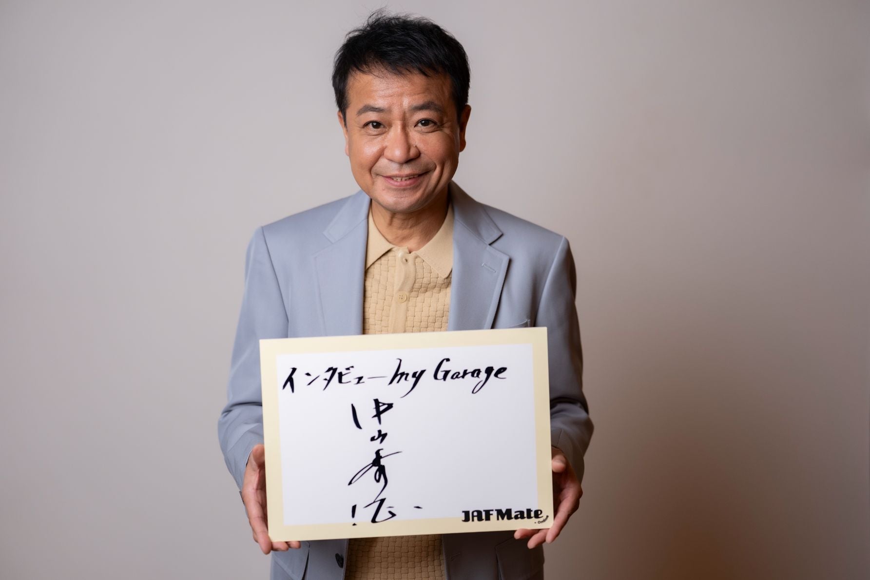 サインを持つ中山秀征さん