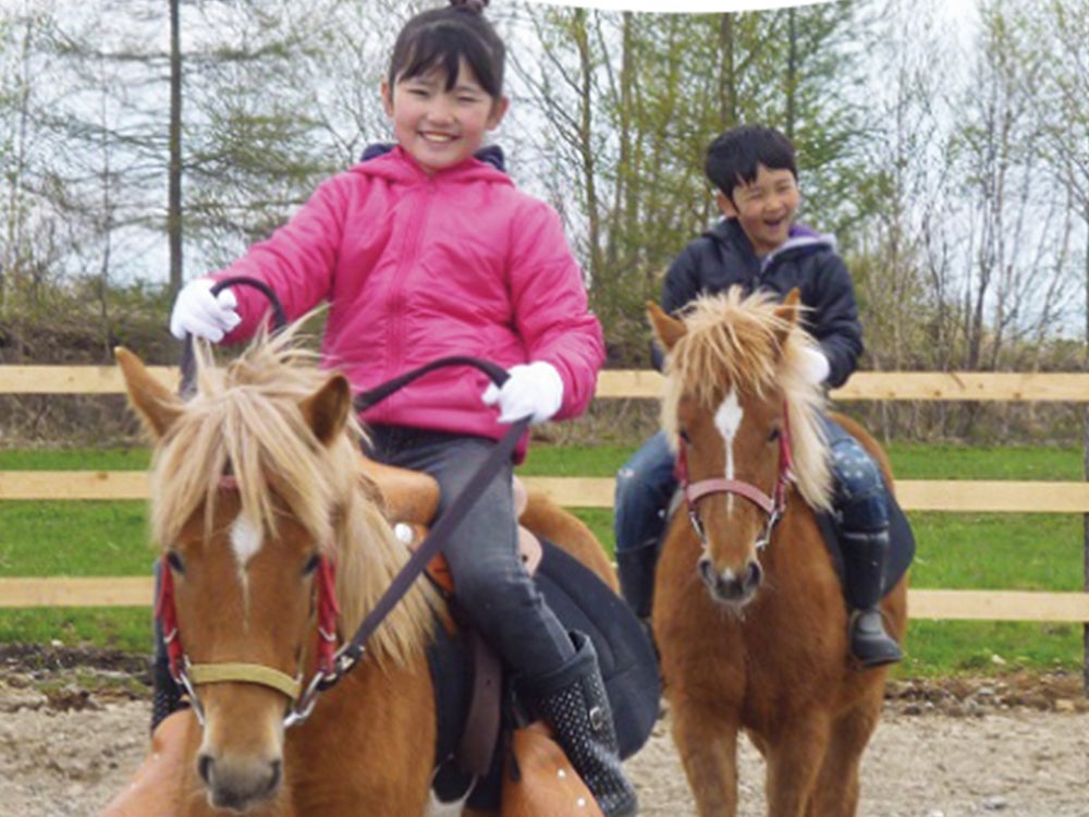 笑顔で乗馬を楽しむ小学生