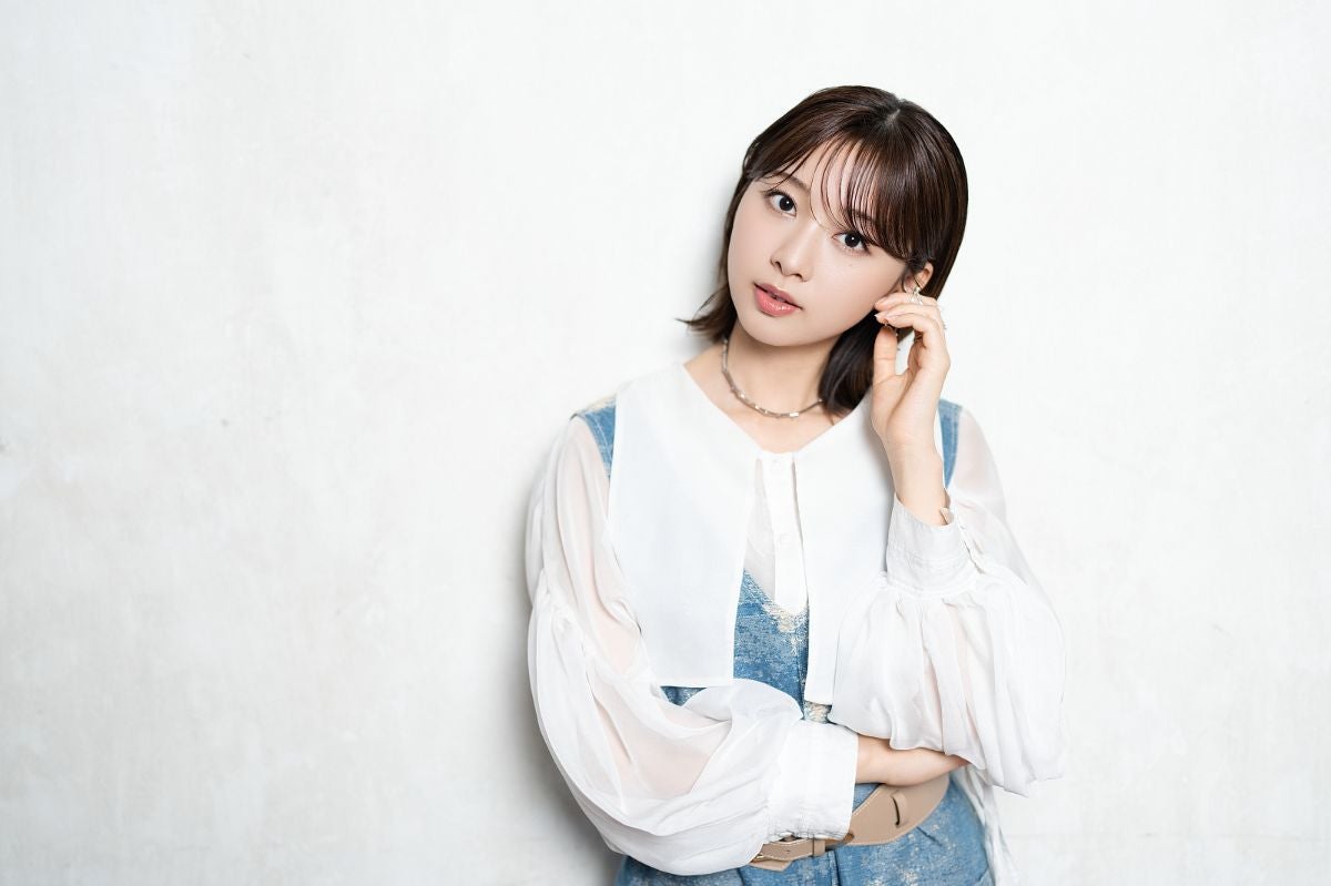手を耳にかけ、ポーズをとる富田鈴花さん