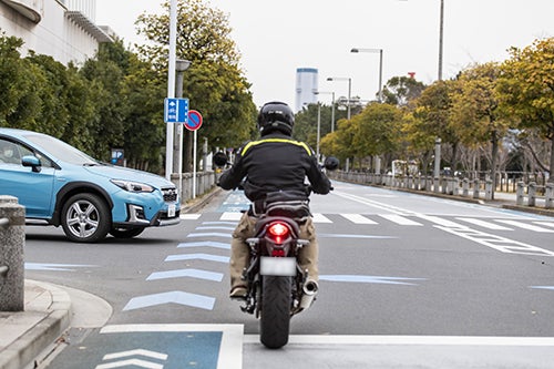 交差点の脇道から進入する自動車を視認して減速するバイク