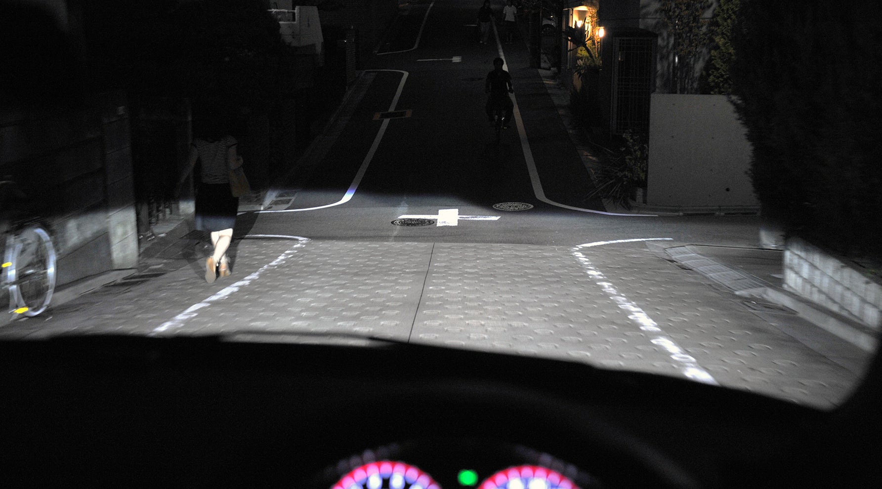 夜間、住宅街の下り坂を走る自車
