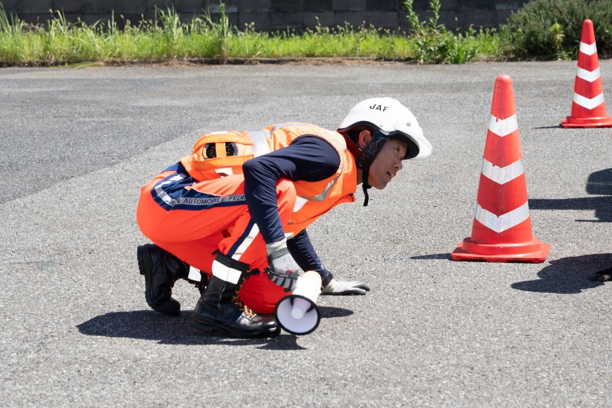 JAF全国ロードサービス競技大会2025 関西本部代表選手｜パイロンのそばで拡声器を持ち、安全確認を行う隊員