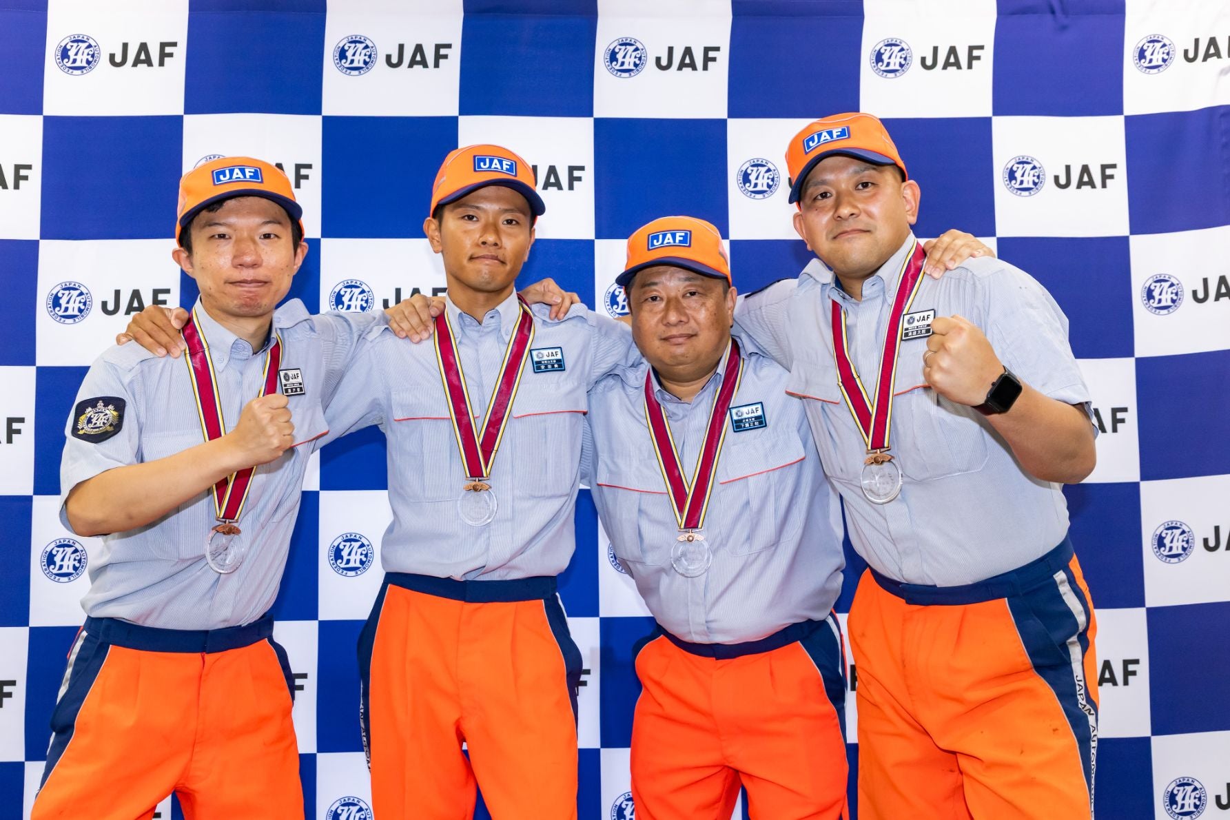 JAFのロゴが入った背景の前で、メダルを首にかけた関西本部の選手4人が肩を組み、拳を掲げてポーズを取っている