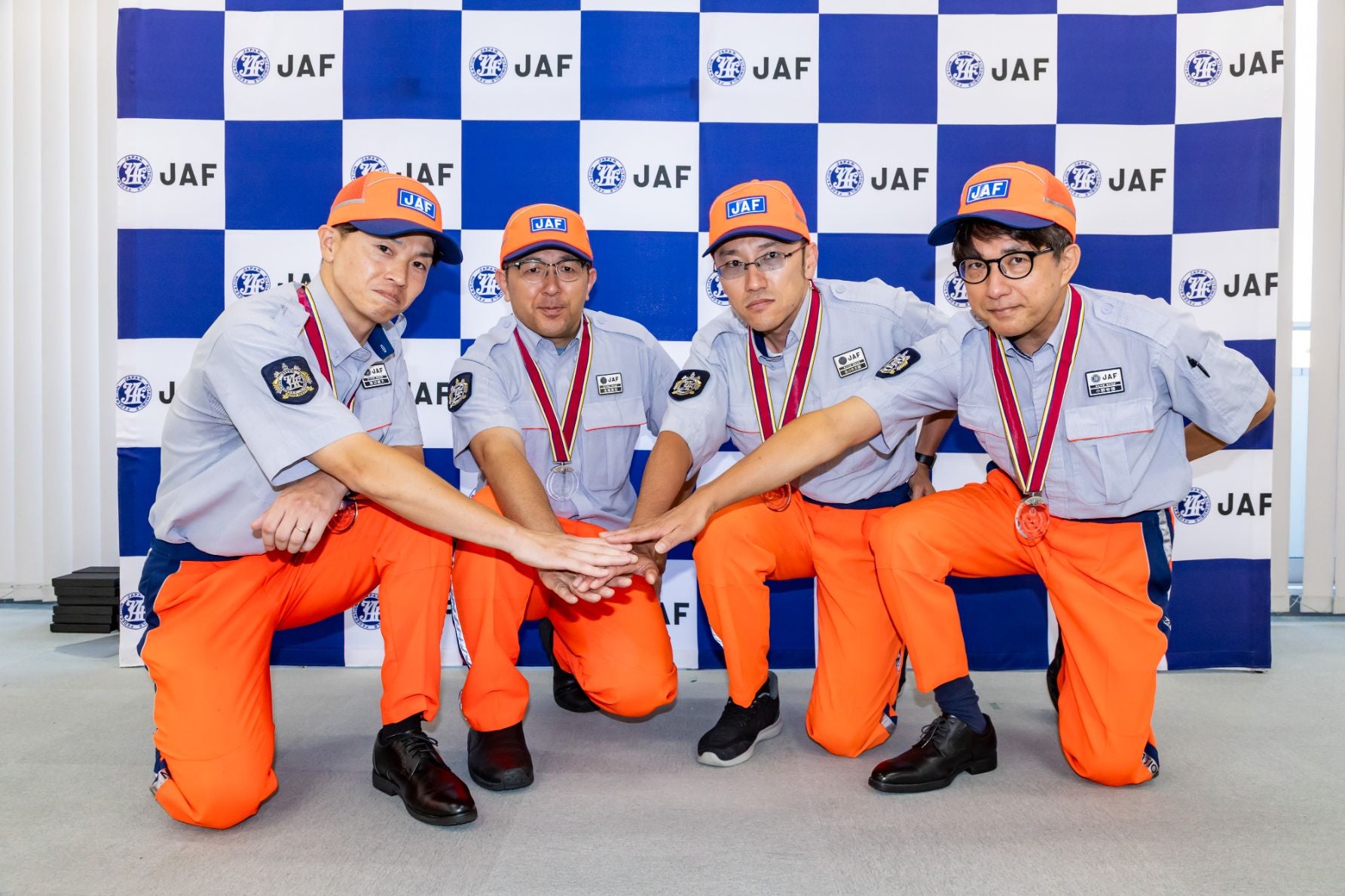 JAFのロゴ入り背景の前で、メダルを首にかけた東北本部の選手が手を重ねてポーズを取っている