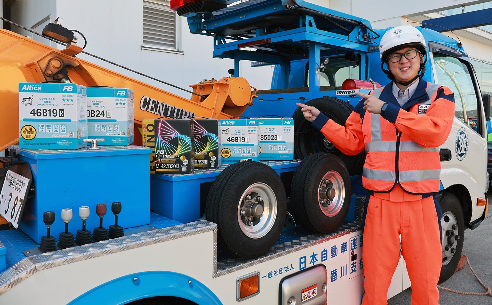 レッカー車に搭載している販売用交換バッテリーを指さす宮岡隊員