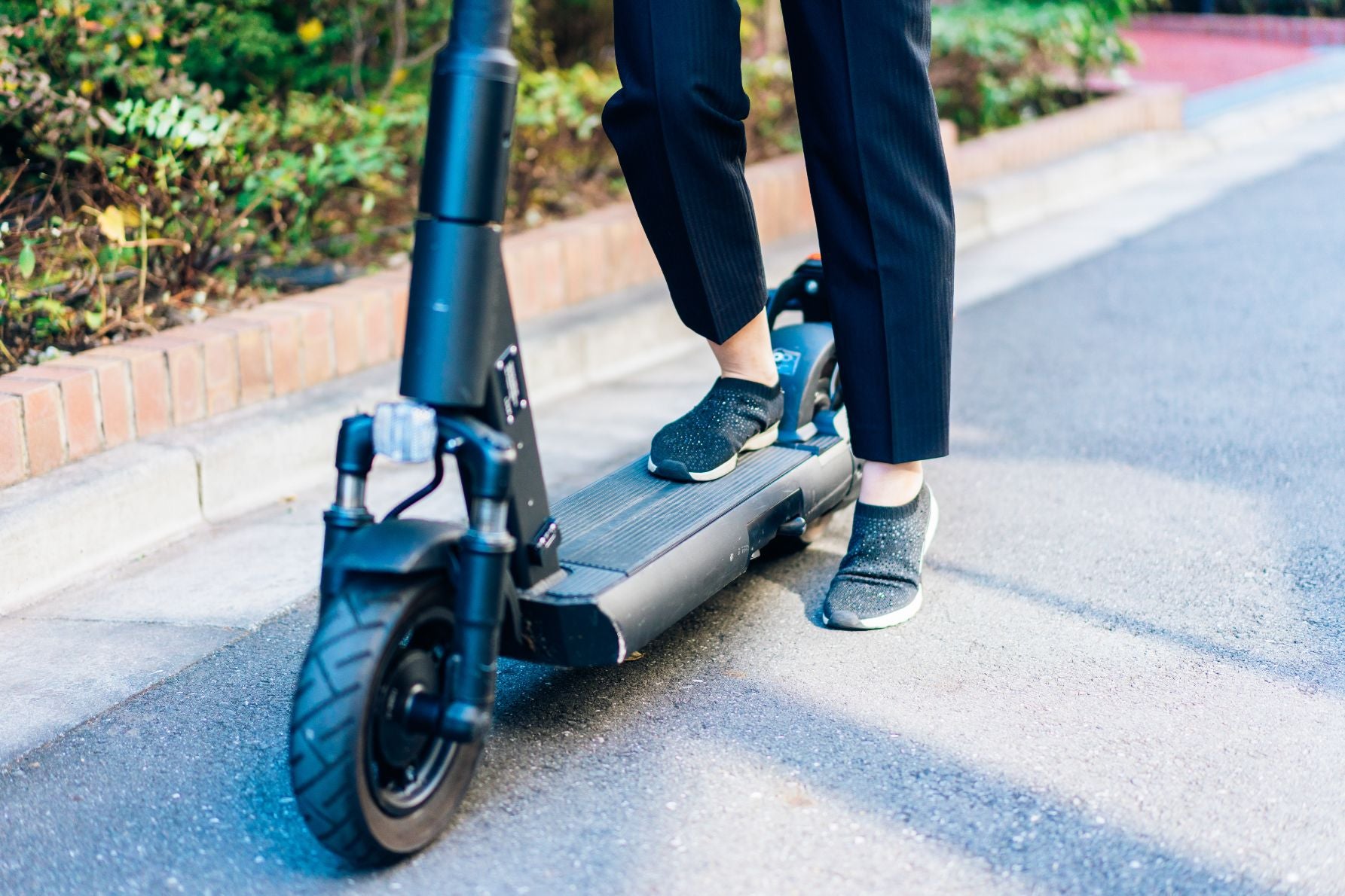 街中で電動キックボードを利用する人物（交通ルールの周知が課題）