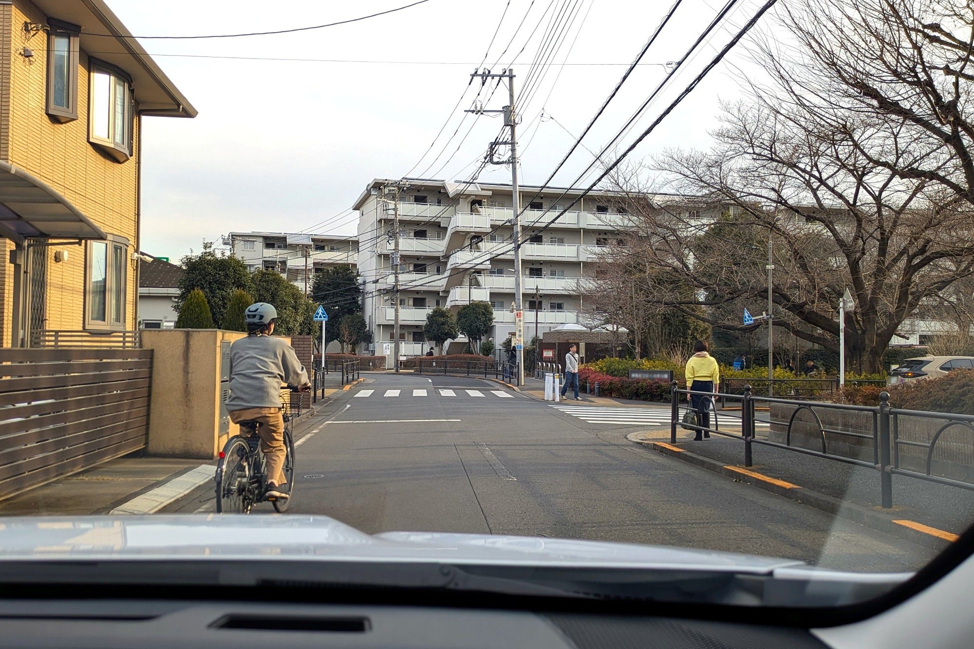 自転車や歩行者がいる信号機のない交差点に差し掛かる自車