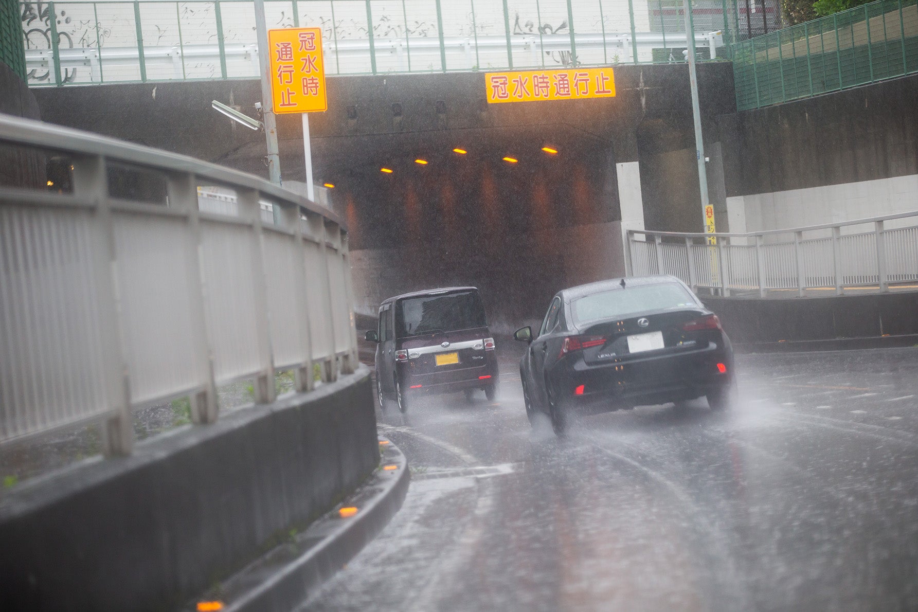 大雨が降る中、アンダーパスに進入する自動車