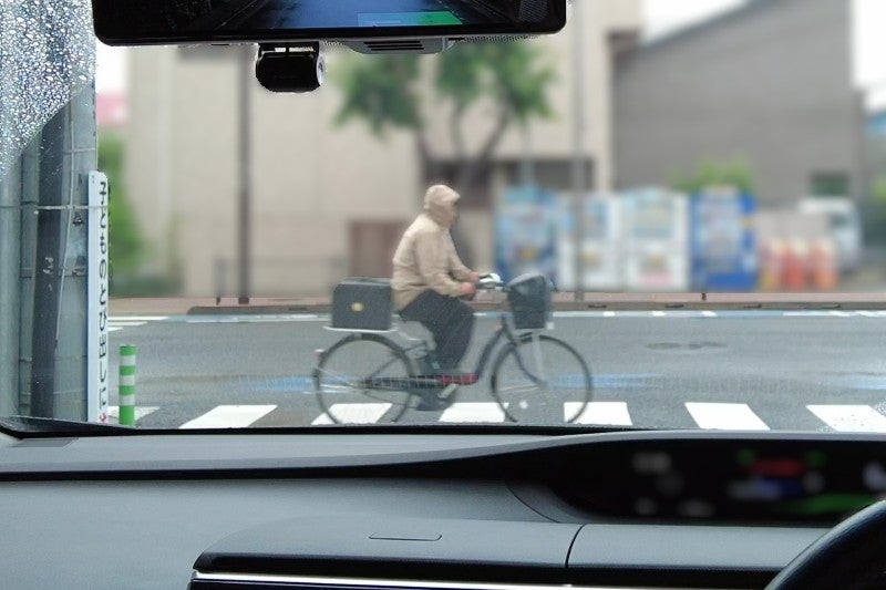 雨具のフードをかぶって自転車に乗る人