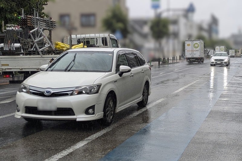 雨の日にヘッドライトをつけて走っているクルマ