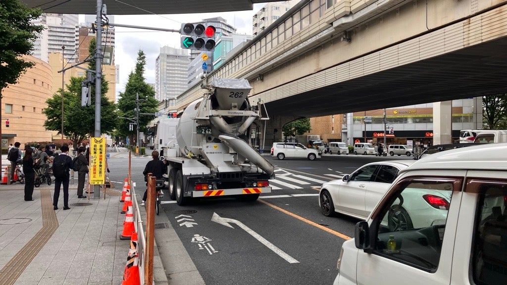 左折専用レーンをコンクリートミキサー車が通行する様子。手前に自転車が停止している