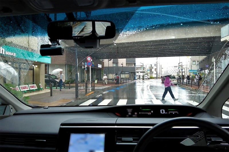 雨の日に信号機のない横断歩道を横断する女性