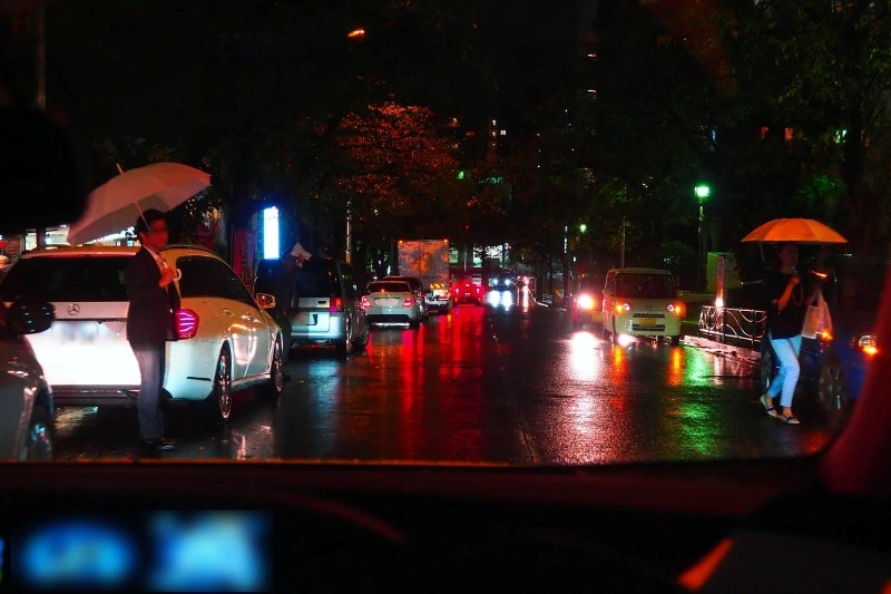雨の降る夜に路駐車が多い道路を走る自車