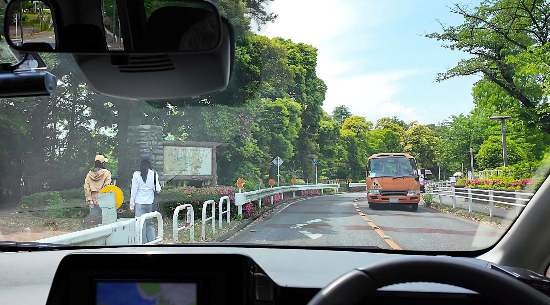 行楽地の道路を走る自車。対向車が続いていて、カーブに差し掛かっている