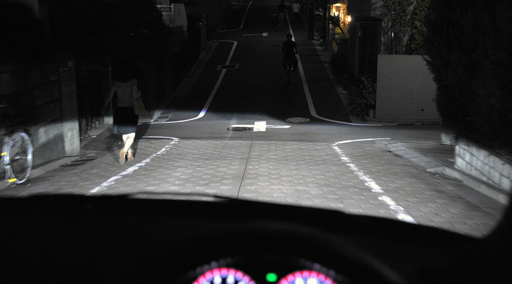 夜間の住宅街の下り坂を走る車から見た写真