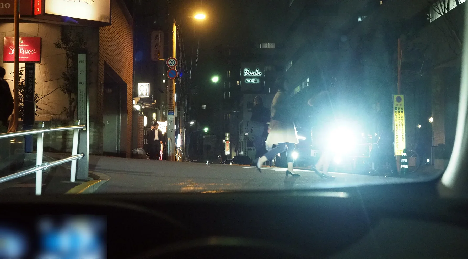 夜間の飲食店街の交差点を走る車から見た写真
