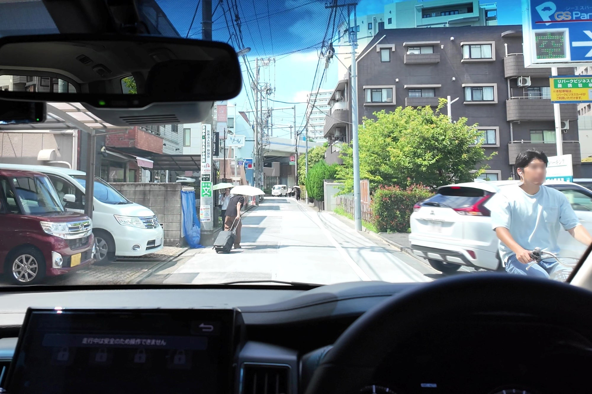右側の駐車場に入る車の後方から自転車が自車の横を通過する場面