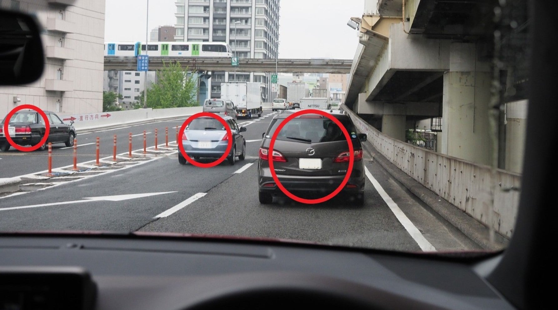 雨の都市高速道路の合流地点で、前車と左前方の車、左側からの合流車に注意する場面